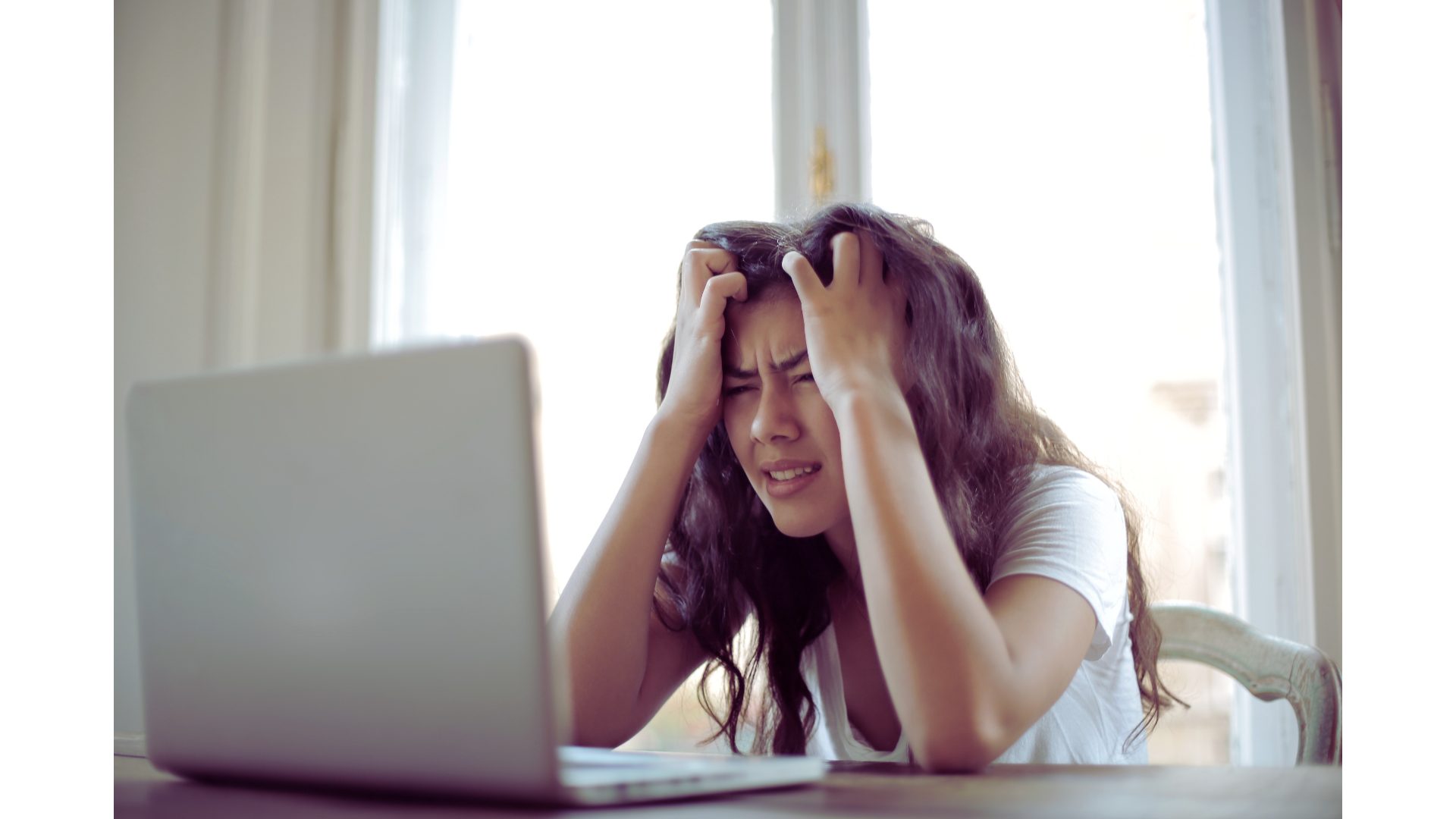 Eine frustrierte Frau sitzt vor einem Laptop, hält sich den Kopf und blickt angestrengt auf den Bildschirm – symbolisch für Probleme oder Unzufriedenheit bei der Zusammenarbeit mit dem aktuellen Datenschutzbeauftragten.